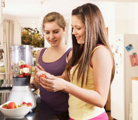Alimentazione e sport: due ragazze preparano uno smoothie alla frutta