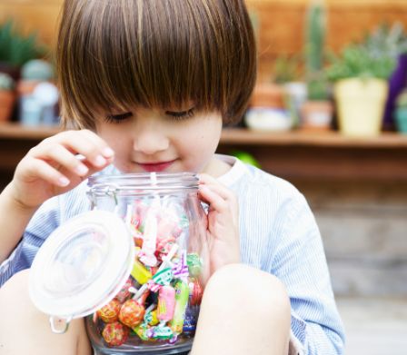 Un garçon regarde dans un bocal de sucreries