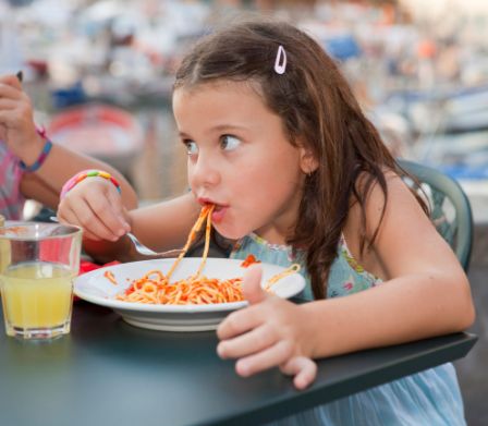 Une fillette mange des spaghettis
