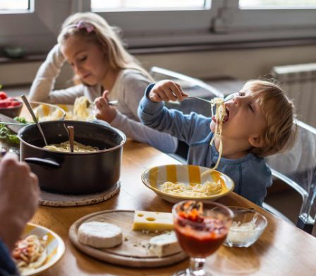 Zwei Kinder beim Spaghetti essen am Familientisch