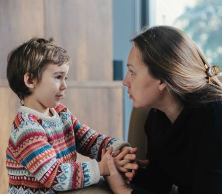 Mutter und Sohn sprechen miteinander und halten sich an der Hand.
