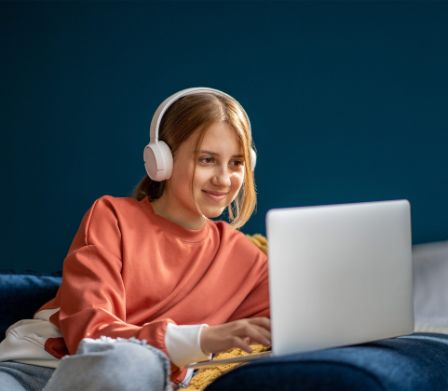 Mädchen mit Kopfhörer tippt auf einem Laptop