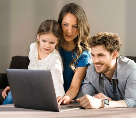 Eltern und Tochter schauen auf einen Laptop