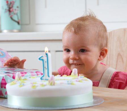 Bebè osserva la torta di compleanno con una candelina
