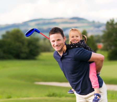 Vater mit Golfschläger und Tochter Huckepack 