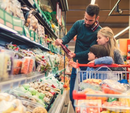 Vater mit zwei Kindern mit Einkaufswagen im Supermarkt