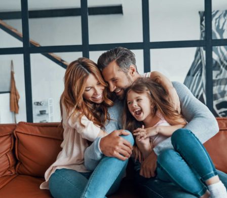 Famille lovée sur le canapé riant en cœur