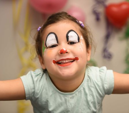 Lachendes Mädchen als Clown geschminkt