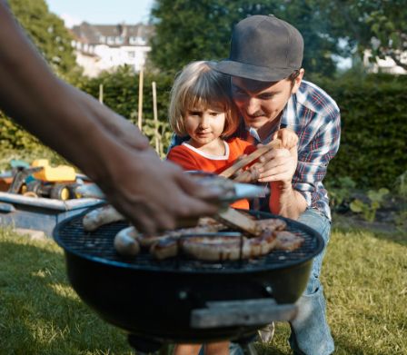 Padre aiuta la figlia a togliere una salsiccia dal grill