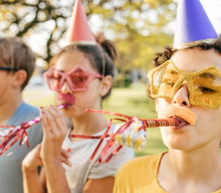 Drei Kinder blasen in Geburtstagströten