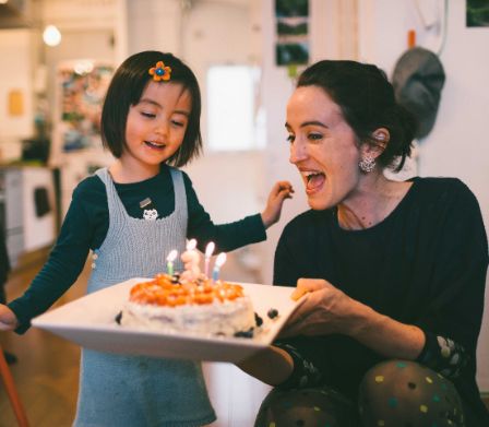 Mutter und Tochter feiern Kindergeburtstag mit einem Kuchen