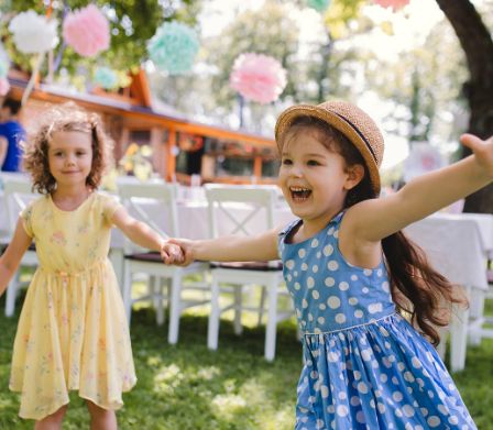 Deux fillettes marchent main dans la main sur une prairie décorée pour la fête