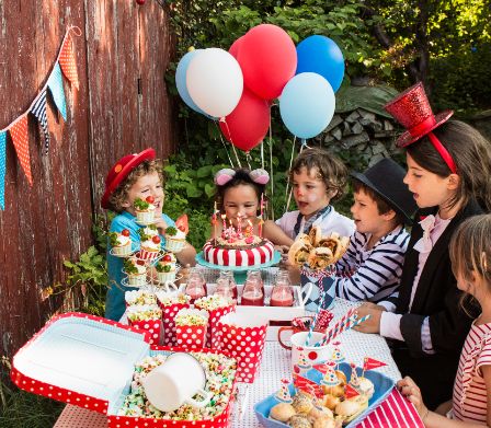 Kinder vor Zirkus-Buffet bewundern die Zirkus-Torte mit brennenden Kerzen
