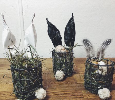 Trois nids de Pâques dans une corbeille en fil de fer avec des oreilles de lapin