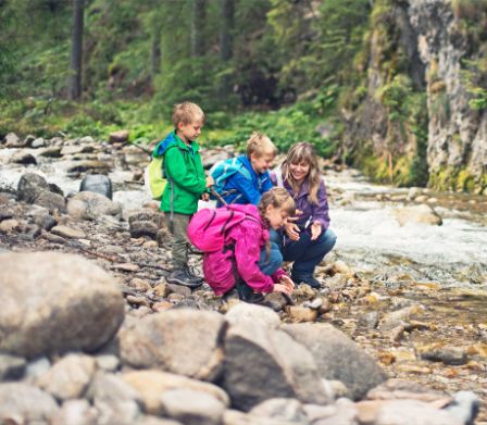 Mutter mit drei Kindern in steinigem Flussbett 