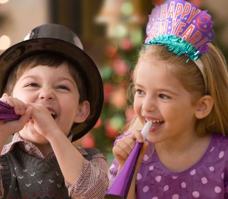 Bube und Mädchen mit Neujahrs-Gadgets und Plastikpfeiffen