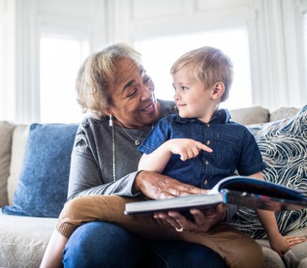 Una nonna seduta sul divano che sfoglia un libro con il nipotino