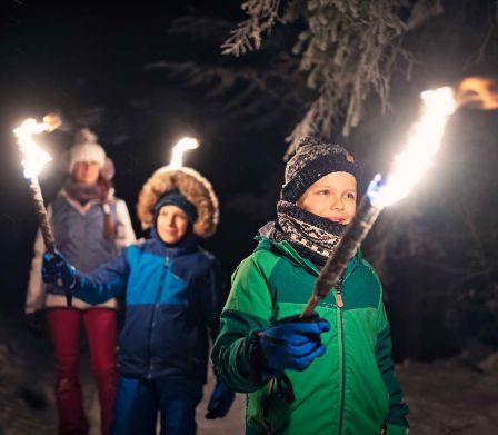 Enfants brandissant des torches lors d’un Noël en forêt