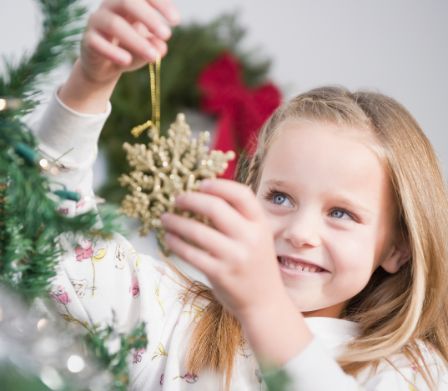 Une petite fille décore le sapin de Noël