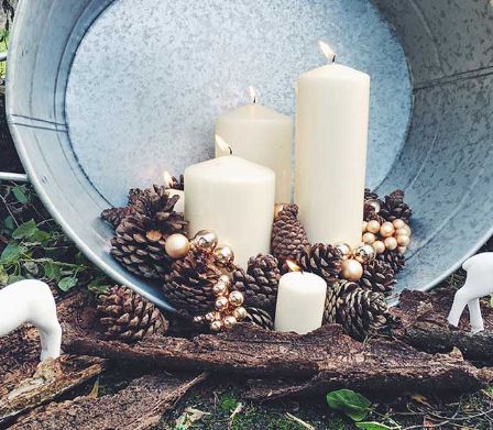Winterliche Aussendekoration aus einem Waschzuber, Rentieren, Kerzen und Tannenzapfen