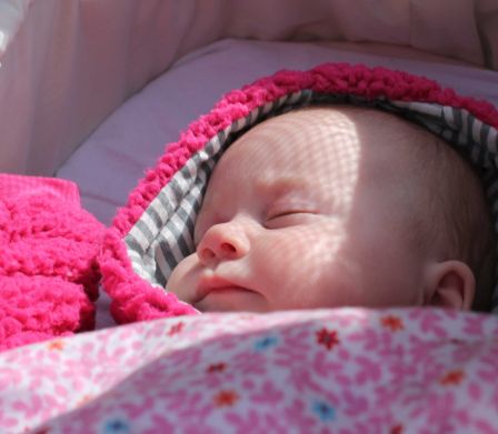 Bébé dans une poussette avec une couverture à fleurs rose