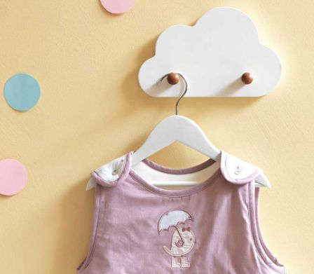 Hellgelbe Wand mit Wolkenhaken mit Babykleid