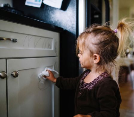 Una bambina toglie strisce colorate dall’armadietto della cucina