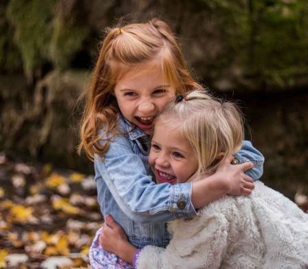 Due bambine si divertono nel bosco autunnale