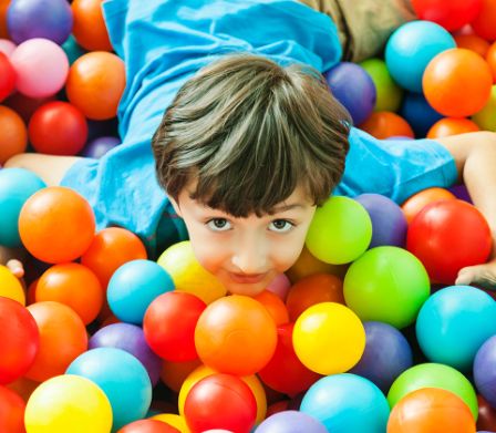 Un ragazzino in una vasca di palline colorate