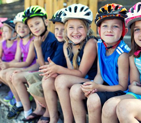 Bambini con casco da bici siedono su una panchina
