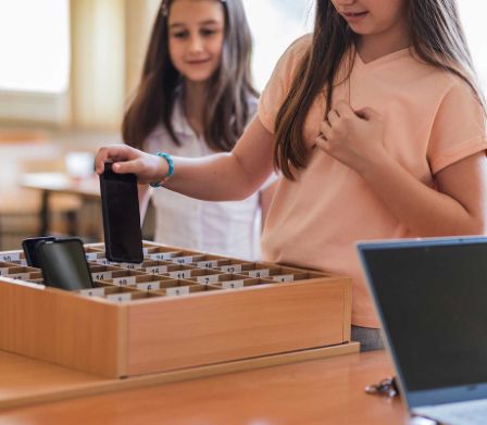 Zwei Mädchen in der Schule, die ihr Handy abgeben