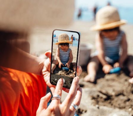 Mutter fotografiert Tochter beim Sand spielen