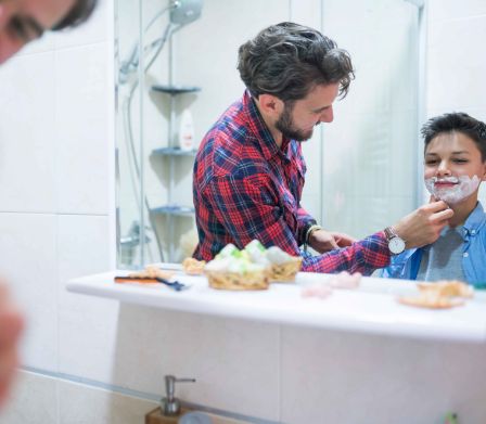 Vater hilft dem Sohn beim Rasieren des ersten Bartwuchses 