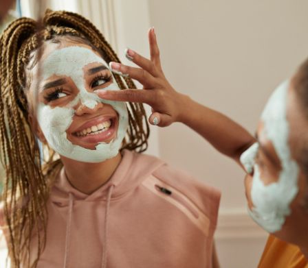 Une adolescente applique un masque pour le visage à son amie.