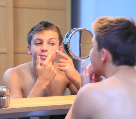 Un ragazzo si osserva allo specchio