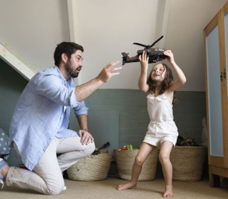 Vater spielt mit der Tochter Spielzeug-Helikopter