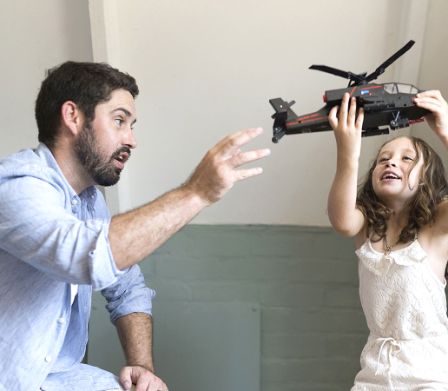 Un papà gioca insieme alla figlia con un elicottero giocattolo