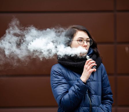 Una ragazza fuma una sigaretta elettronica