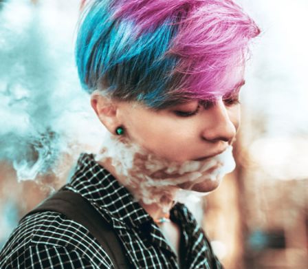 Eine junge rauchende Frau mit bunten Haaren 
