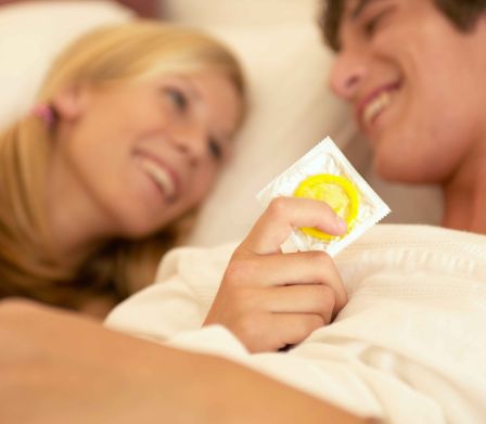 Contraceptifs pour jeunes: un jeune couple avec un préservatif dans la main