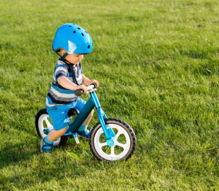 Un bambino va in bicicletta con il casco