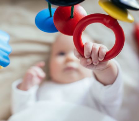Un bebè afferra un anello di presa mentre è sdraiato