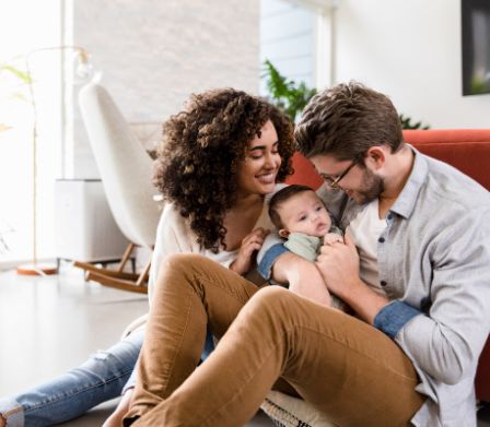 Jeunes parents épanouis tenant leur petit bébé dans les bras