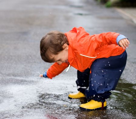 Bebè con stivali di gomma e abbigliamento da pioggia