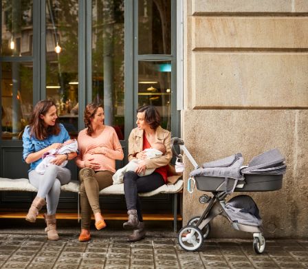 Schwangere und zwei junge Mütter unterhalten sich vor einem Café