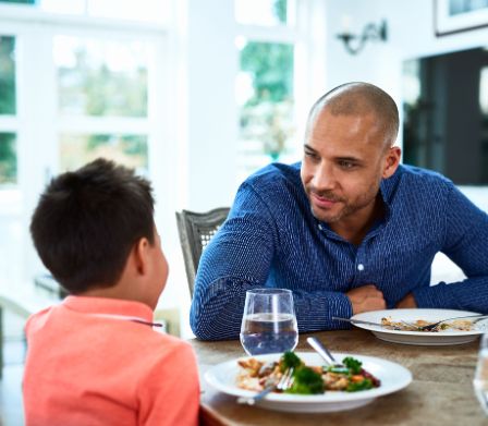 Un padre spiega al figlio come ci si comporta a tavola