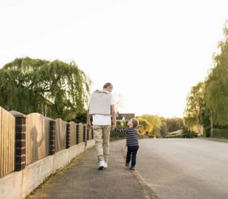 Un père marche avec son enfant le long de la route.
