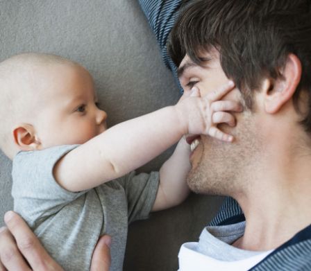 Baby tastet das Gesicht von seinem Vater