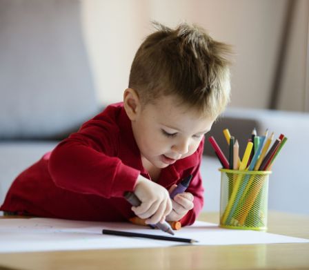 Un bambino disegna entusiasta con le matite colorate