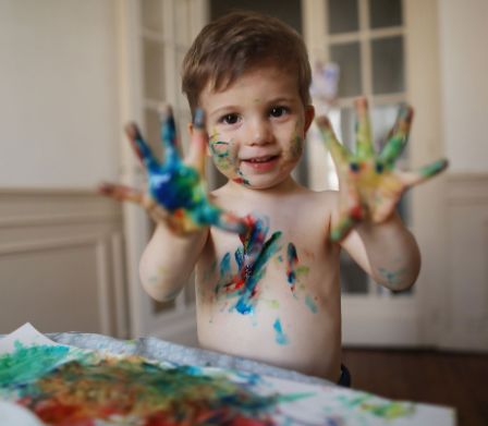 Un ragazzino disegna con i colori a dita 